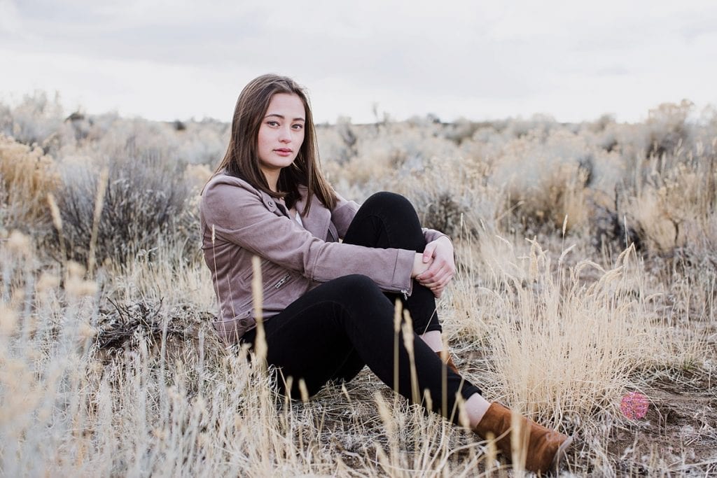 Girl sitting in desert for senior pictures in Bend Oregon